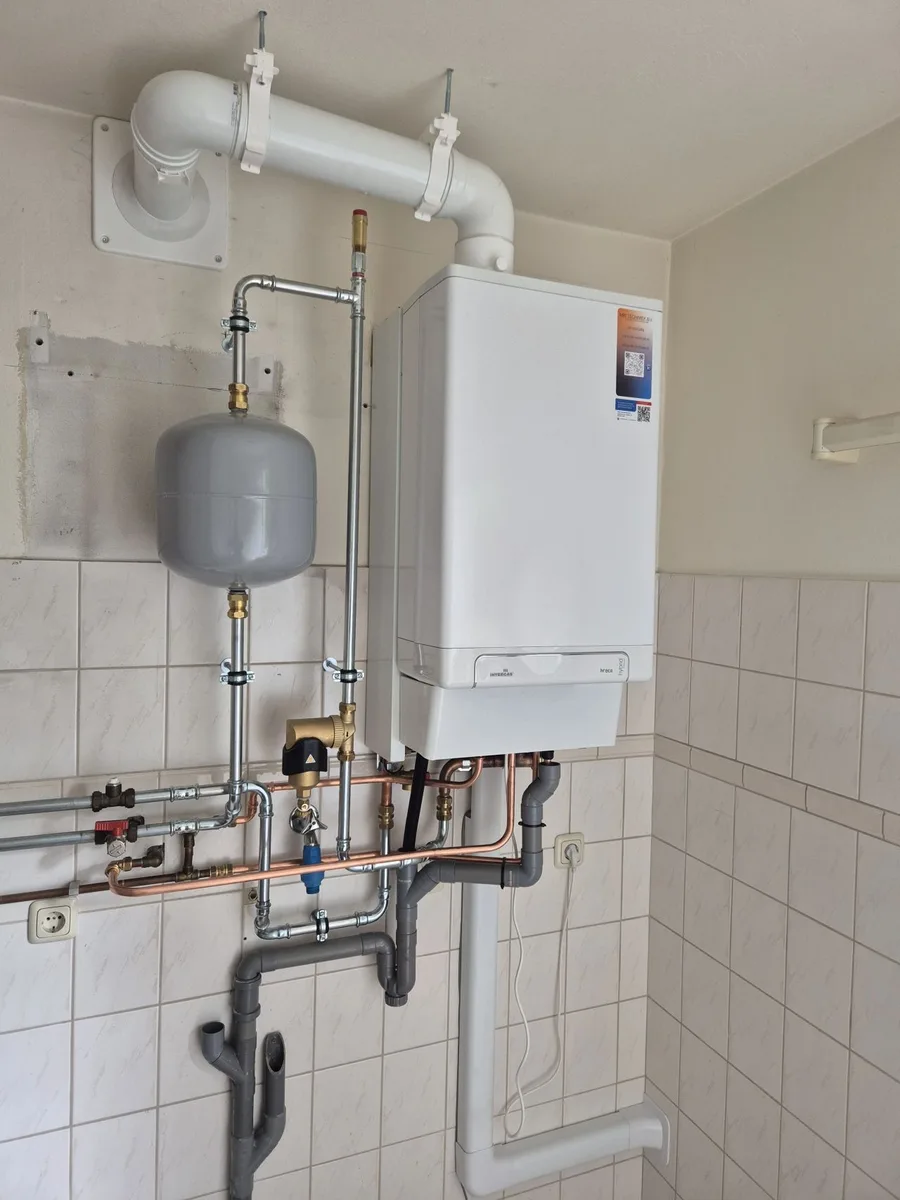 Nieuw geplaatste cv-ketel met expansievat en koperen leidingwerk op een betegelde wand, afgemonteerd door MKI-Techniek