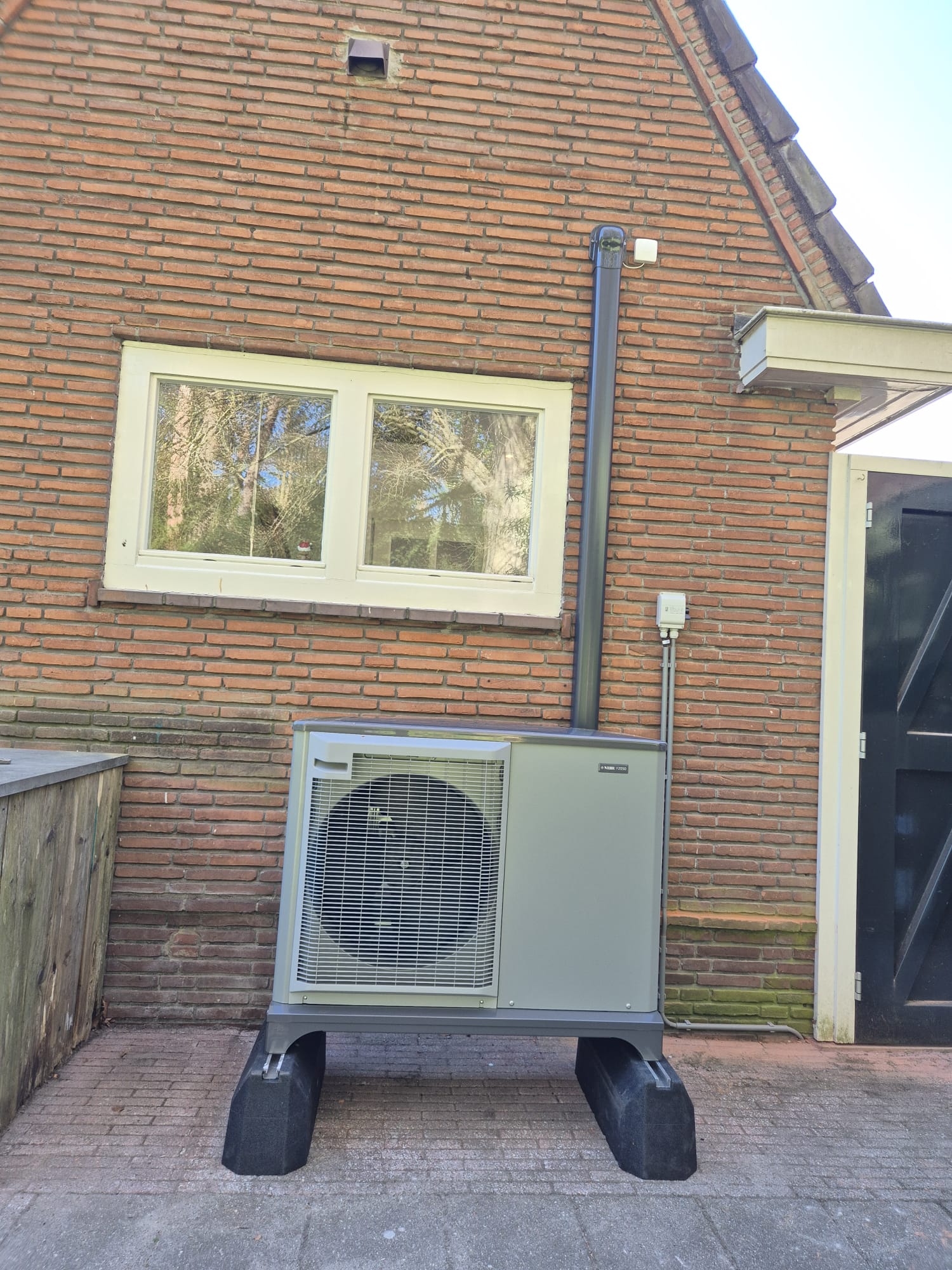 NIBE F2050 warmtepomp buitenunit tegen bakstenen gevel van jaren dertig woning in Zeist